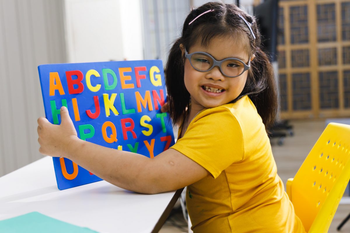 Asian girl with Down's syndrome play alphabet puzzle toy.