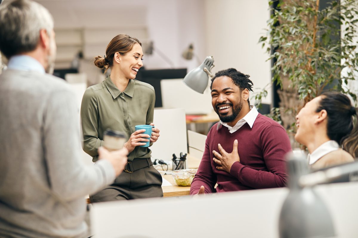 Multi-ethnic group of entrepreneurs laughing while talking to each other on a break in the office.