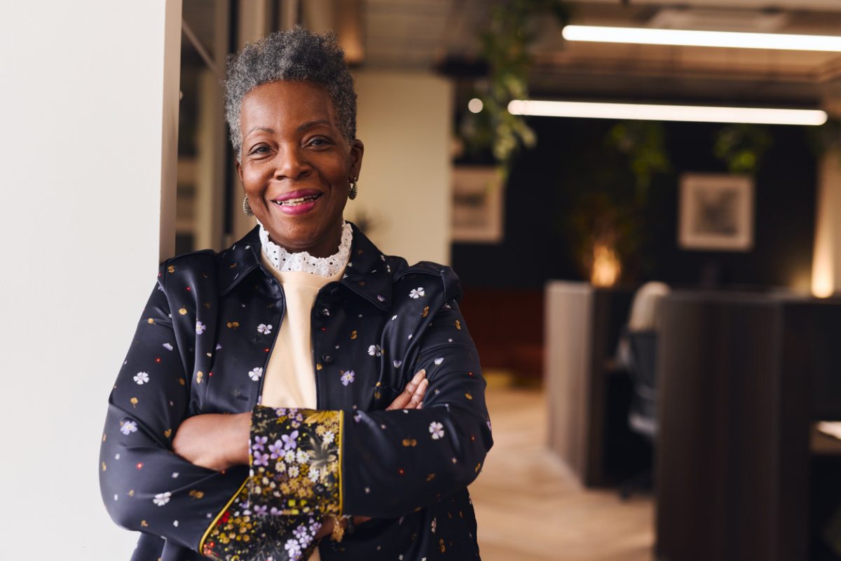 Portrait of confident senior black woman smiling and looking at camera with arms folded