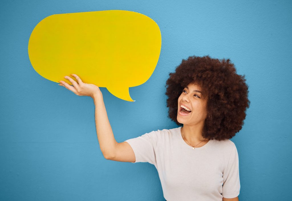 Black woman with yellow speech bubble, afro and blue background mockup space for advertising or product placement. Smile, announcement sign and woman excited for small business discount sale launch.