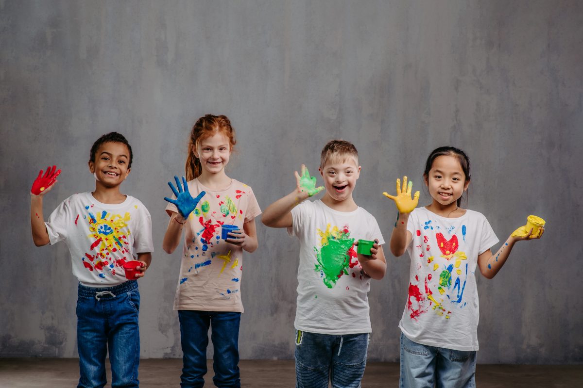 Portrait of happy kids with finger colours and painted t-shirts.